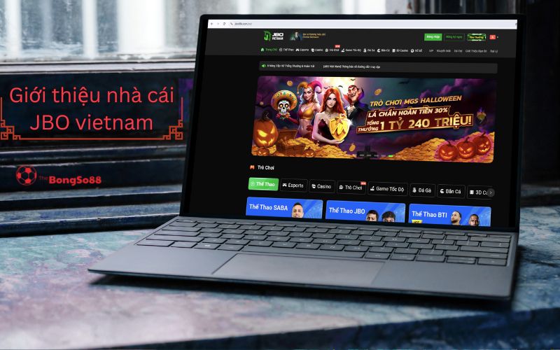 Laptop hiển thị trang chủ JBO Vietnam, banner "Trò Chơi MGS Halloween... 240 Triệu" và tiêu đề "Giới thiệu nhà cái JBO vietnam".
